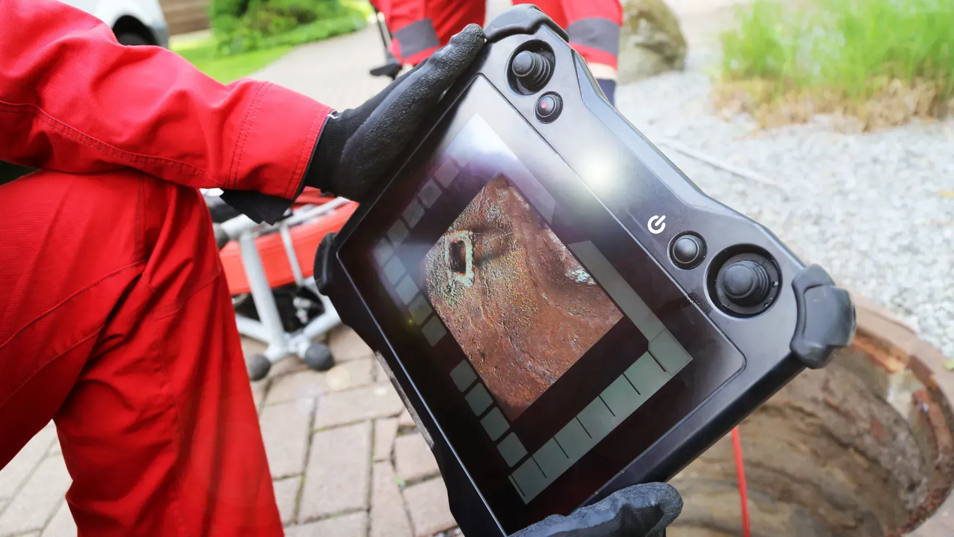 A person in a red jumpsuit is holding a tablet in their hands.
