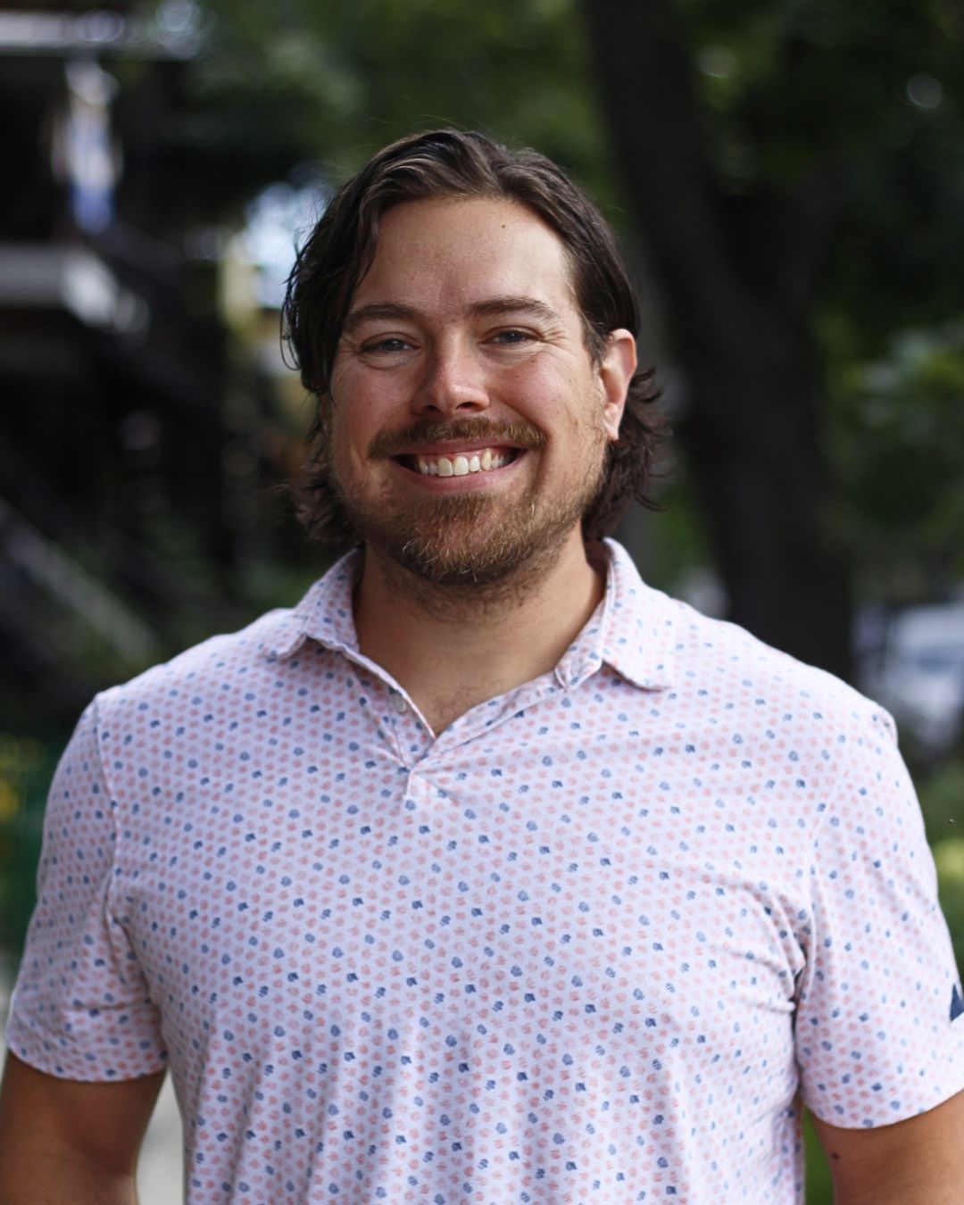 Un homme en chemise papillon est appuyé contre un mur sur une photo en noir et blanc.