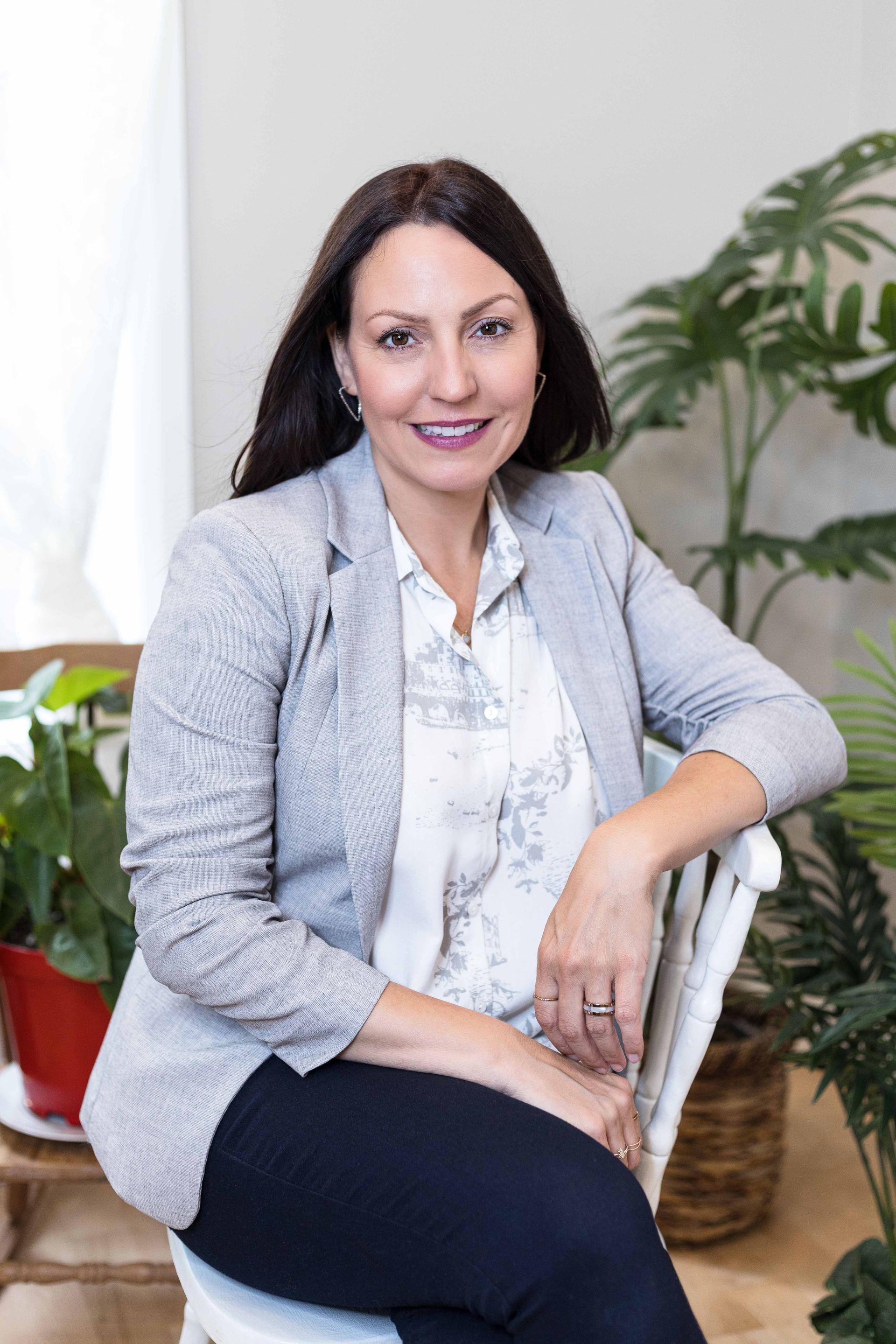 Une photo en noir et blanc d’une femme en pull debout devant un arbre.