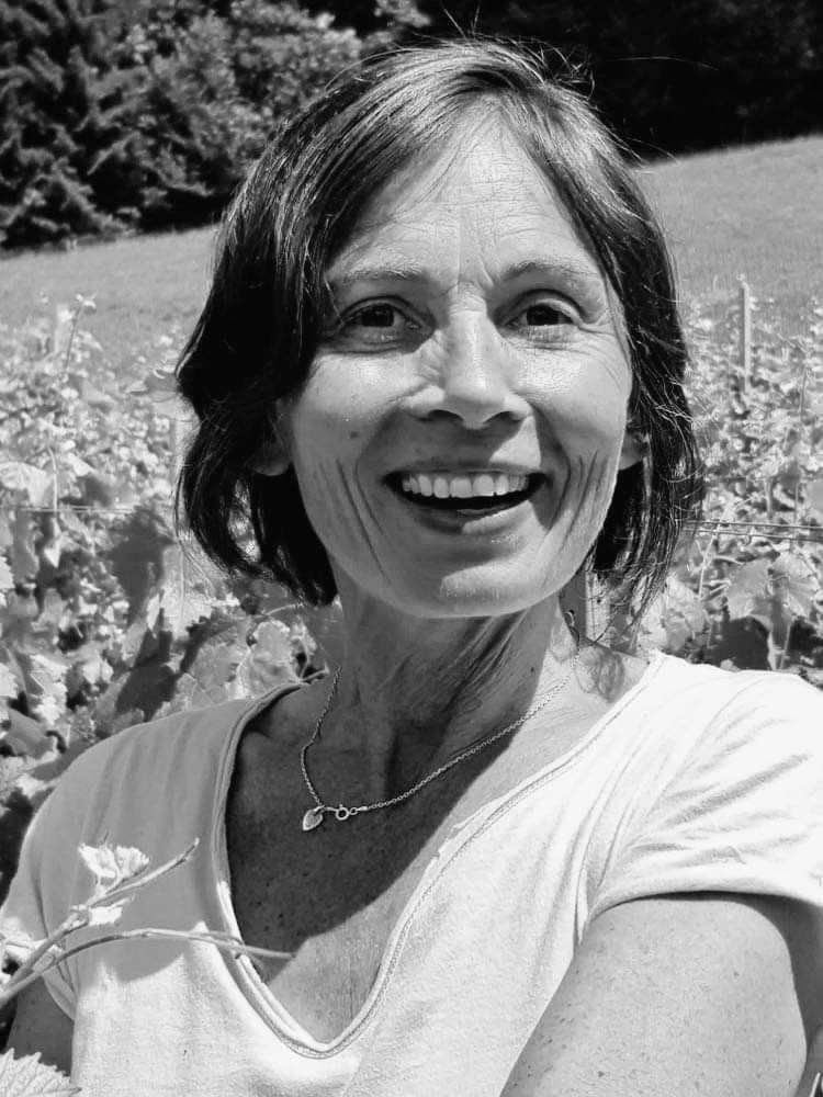Une femme en chemise blanche sourit sur une photo en noir et blanc.