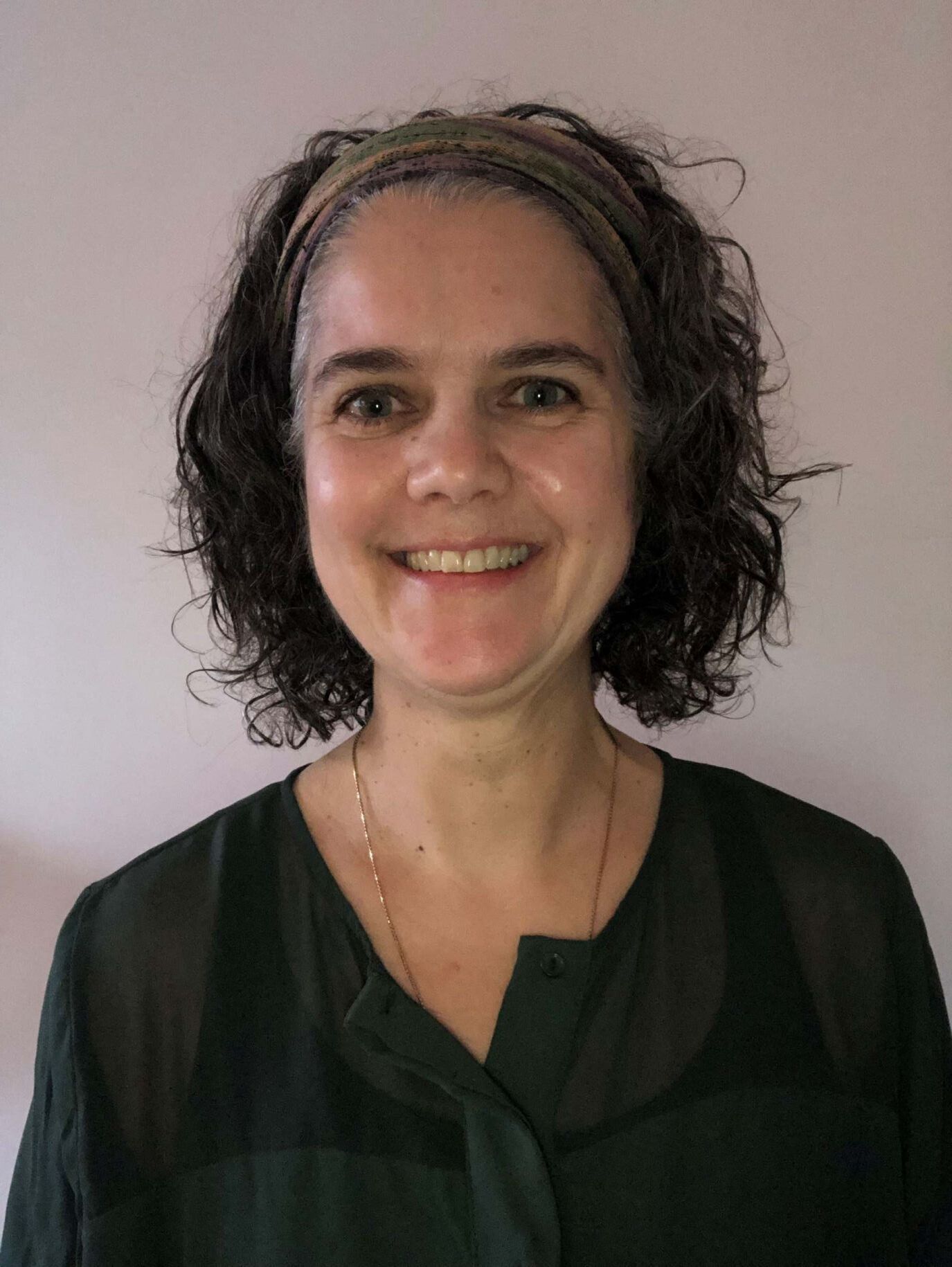 Une photo en noir et blanc d’une femme en pull debout devant un arbre.