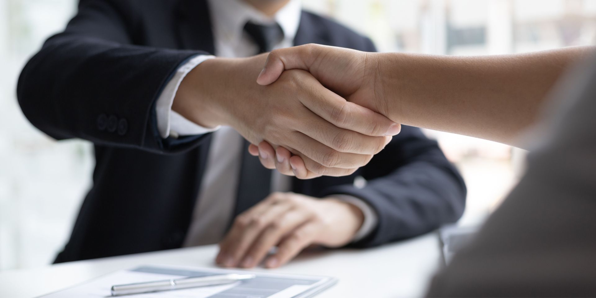 A man and a woman are shaking hands over a table.