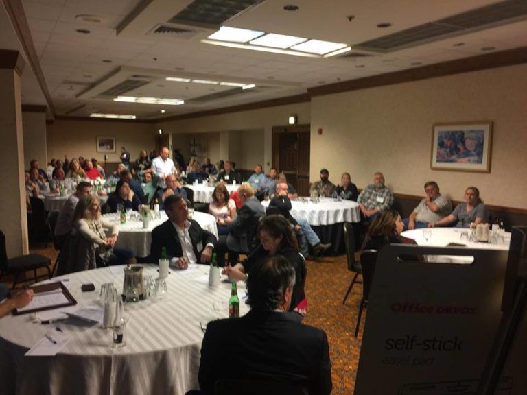 A group of people are sitting at tables in a room with a sign that says self-service