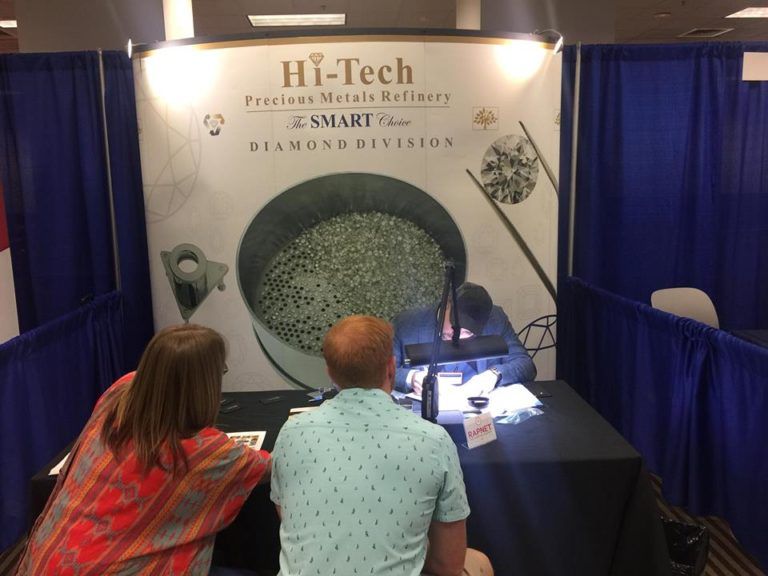 Two people sit at a table in front of a hi-tech sign