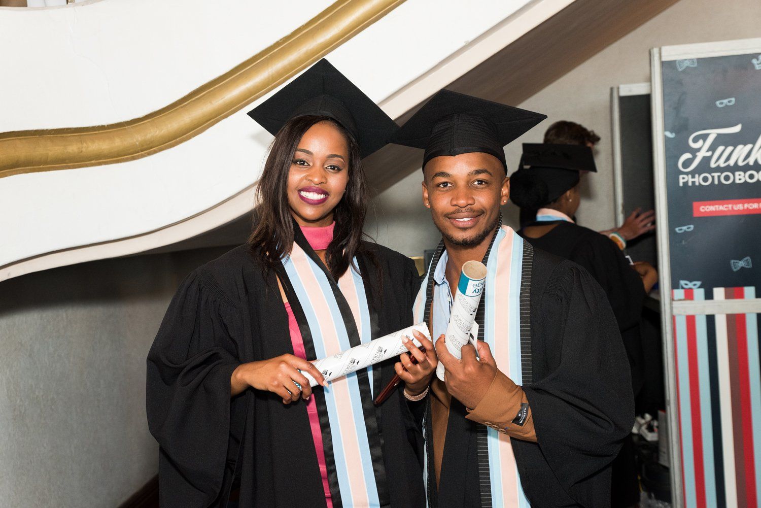 A man and a woman in graduation caps and gowns are posing for a picture.