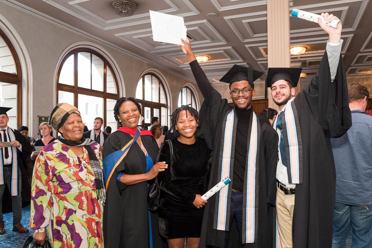 A group of graduates are posing for a picture with their diplomas.