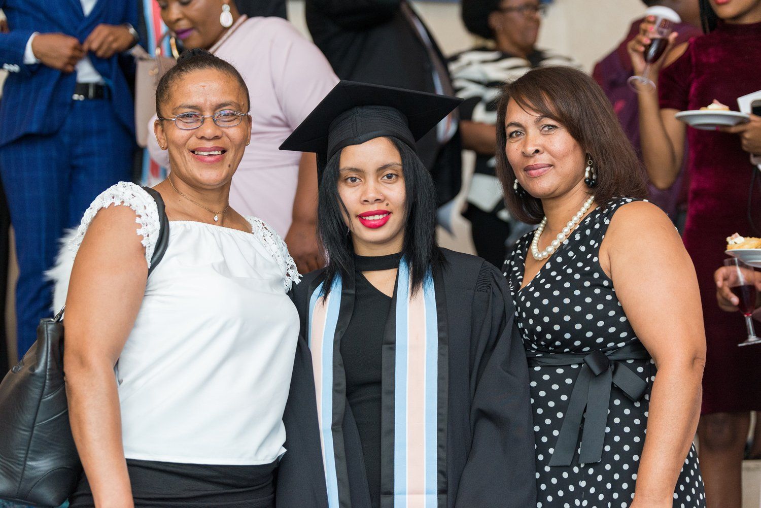Three women are posing for a picture with a graduate in a cap and gown.