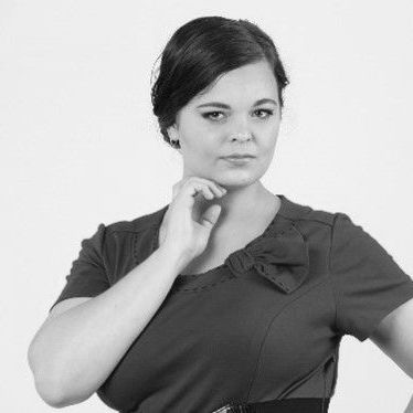 A black and white photo of a woman in a dress with her hand on her chin.