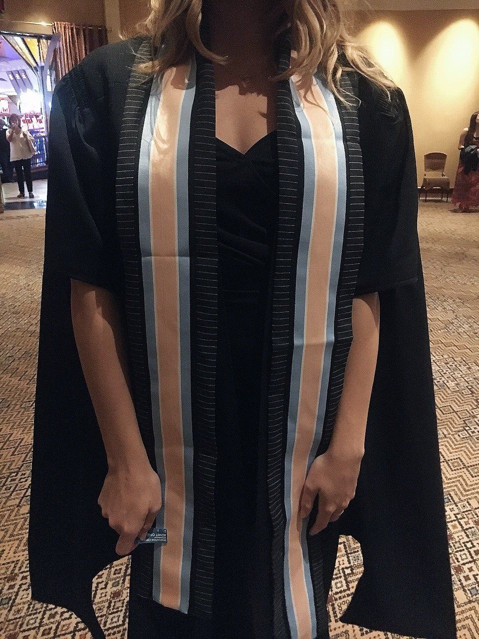 A woman wearing a black cape and a striped sash