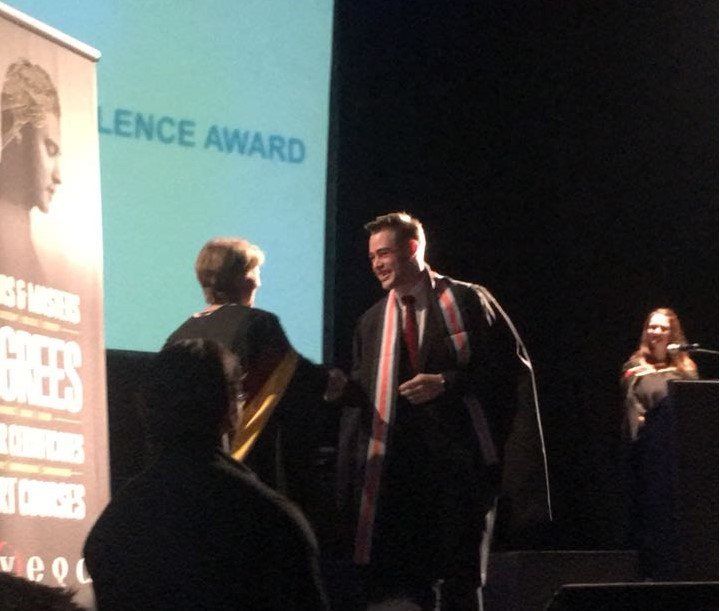 A man standing in front of a screen that says lence award