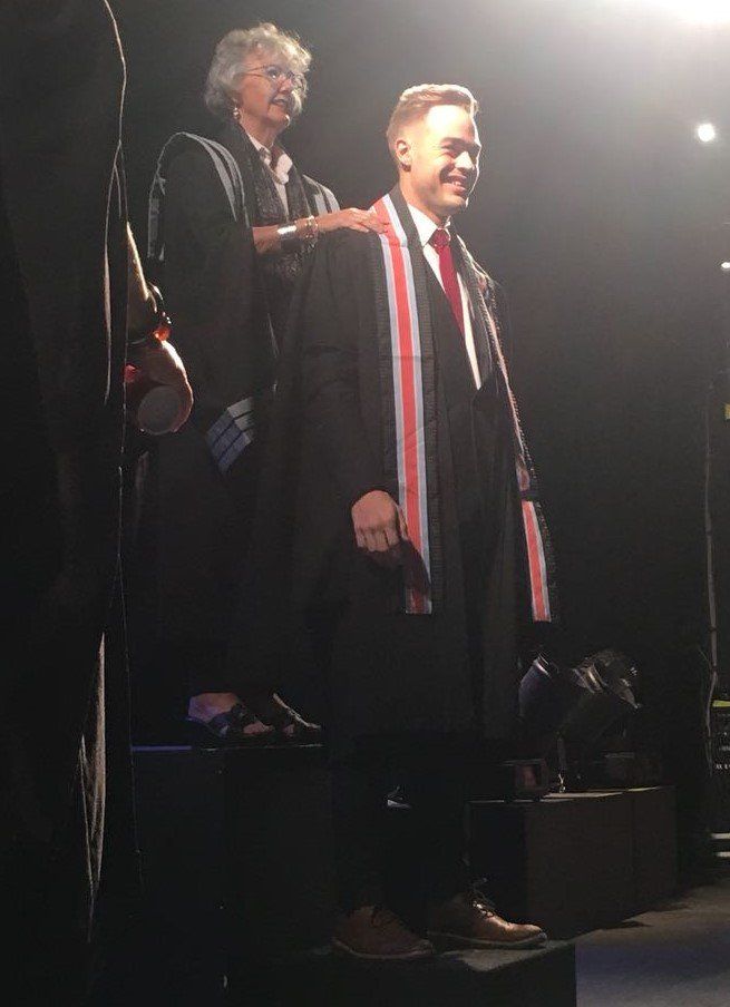 A man in a graduation cap and gown is standing on a stage