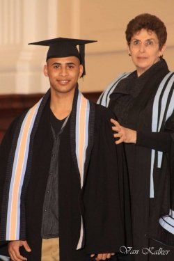 A man in a graduation cap and gown stands next to a woman