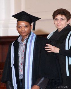 A man in a graduation cap and gown stands next to a woman