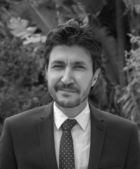 A man in a suit and tie is smiling in a black and white photo.