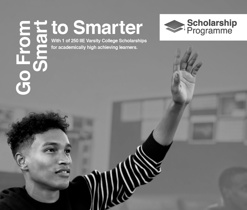 A black and white photo of a young man raising his hand in a classroom.