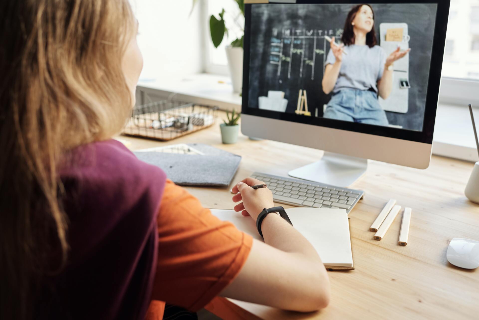 A woman is sitting at a desk looking at a computer screen.
