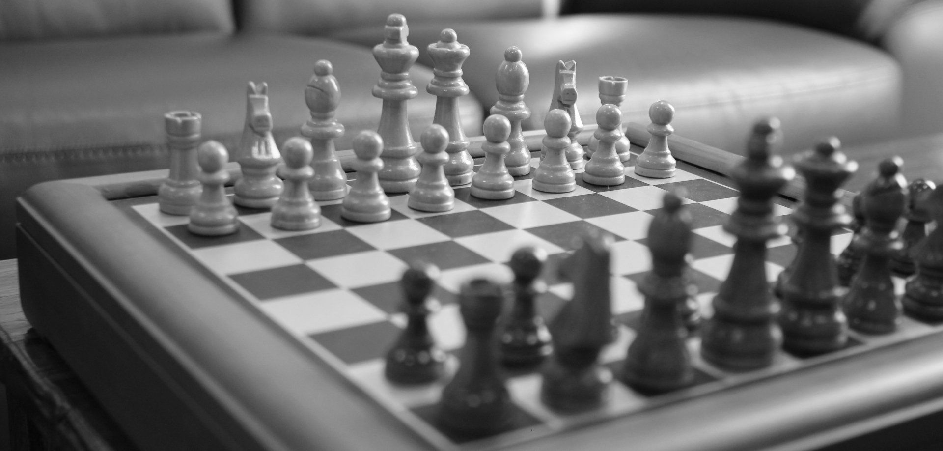 A black and white photo of a chess board with chess pieces on it.