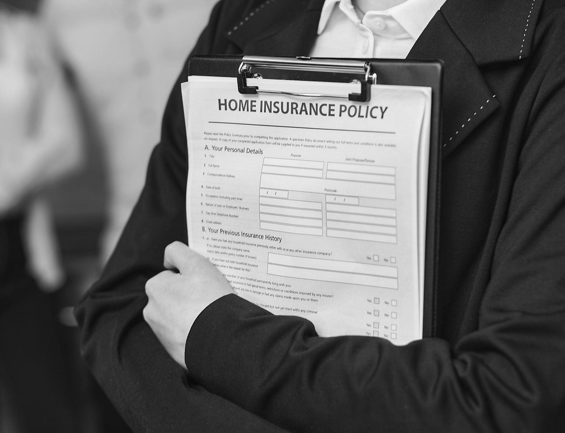 A person is holding a clipboard with a home insurance policy on it.