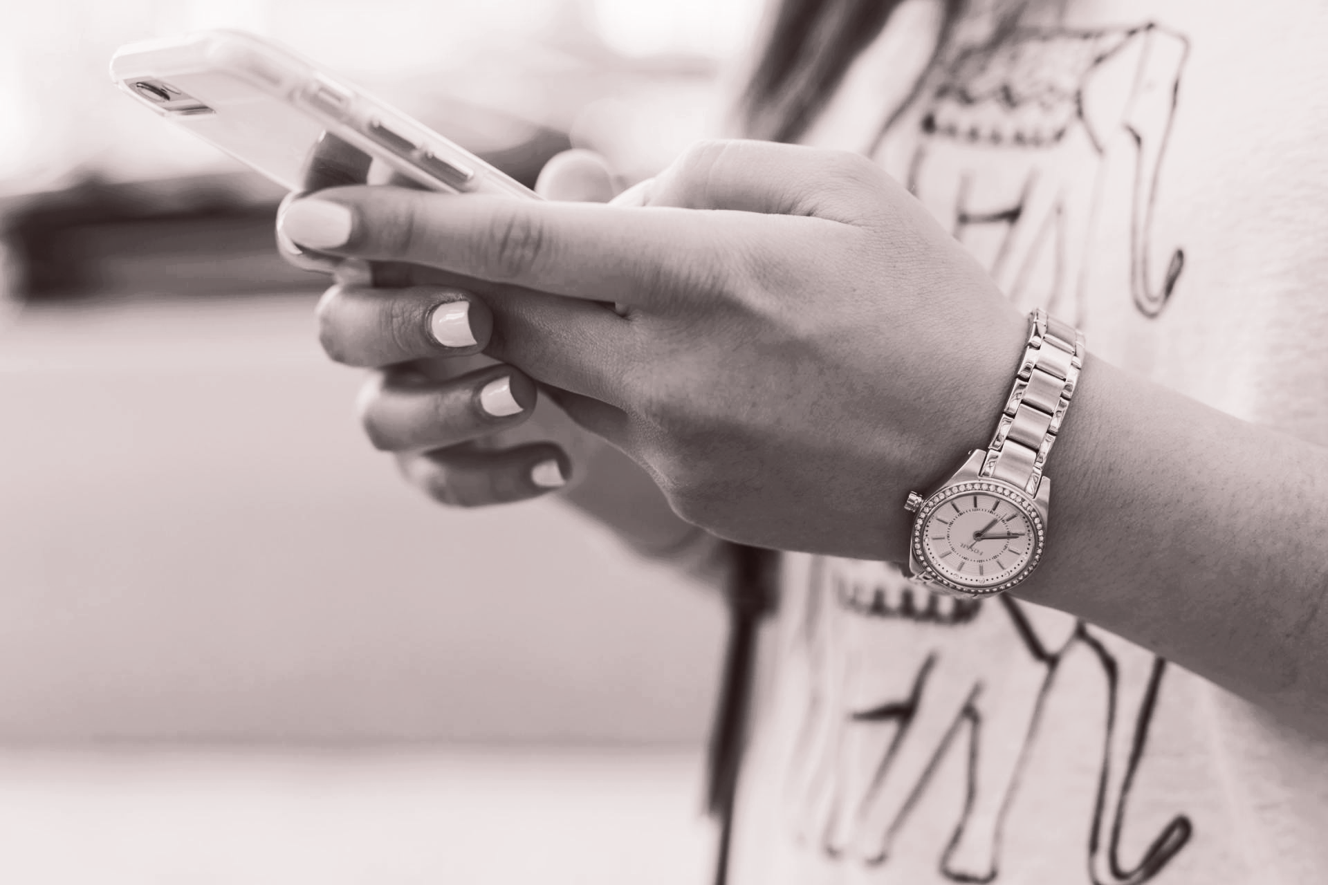 A woman wearing a watch is holding a cell phone in her hands.