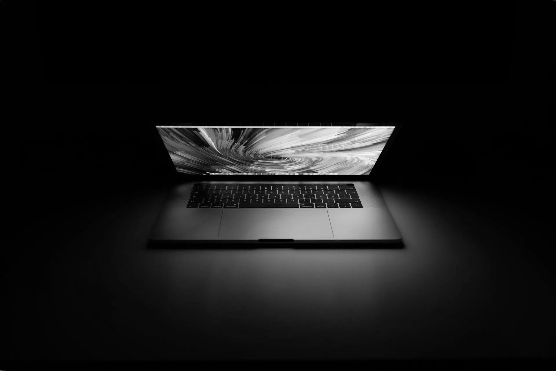 A black and white photo of a laptop computer in the dark.
