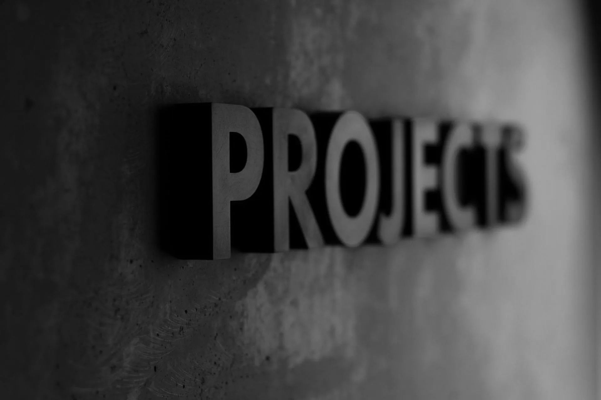A black and white photo of the word projects on a wall.