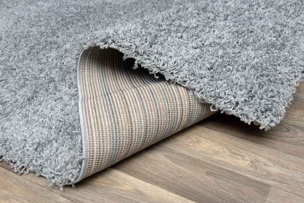 The Back of a Grey Rug is Shown on a Wooden Floor — Aussie Carpets & Vinyl In Buderim, QLD
