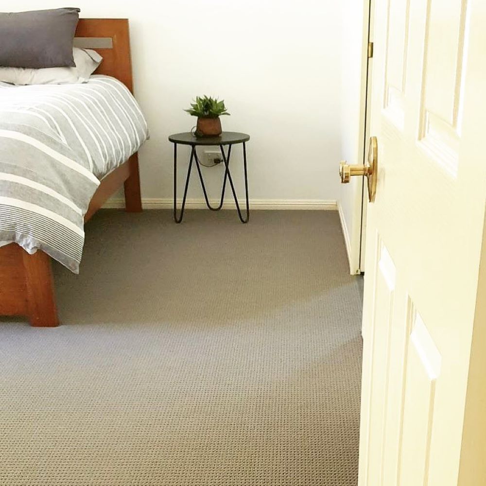 A Bedroom With a Bed and a Table With a Plant on It — Aussie Carpets & Vinyl In Maleny, QLD