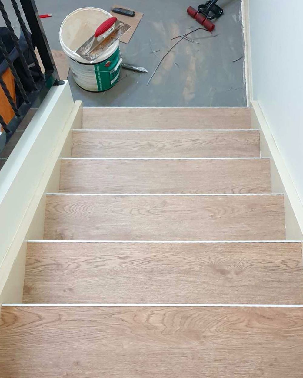 A Wooden Staircase With a Bucket of Paint and Tools on the Floor — Aussie Carpets & Vinyl In Beerwah, QLD