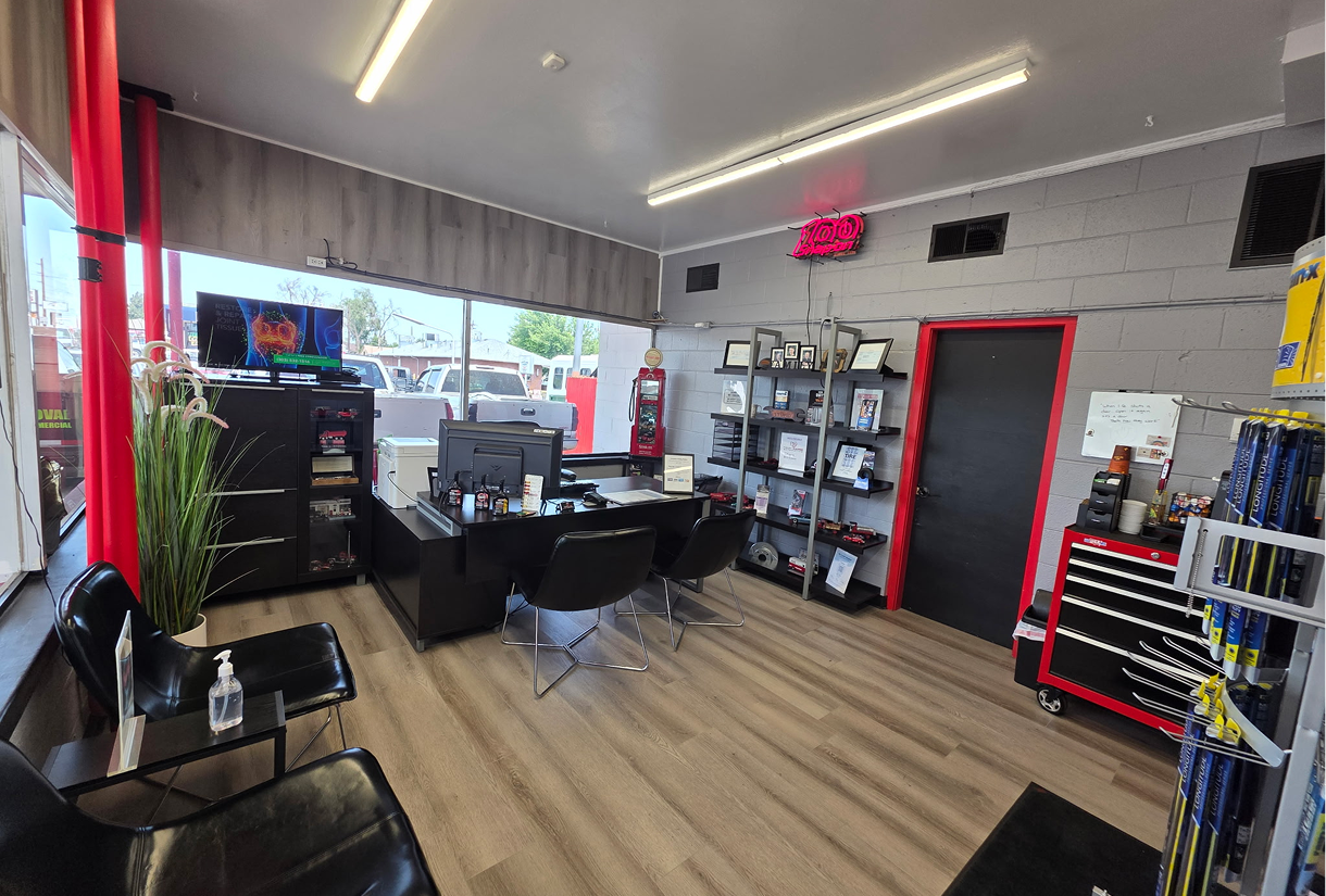 Interior of a car repair shop waiting area with black chairs, a desk, and product displays. | Front Range Auto