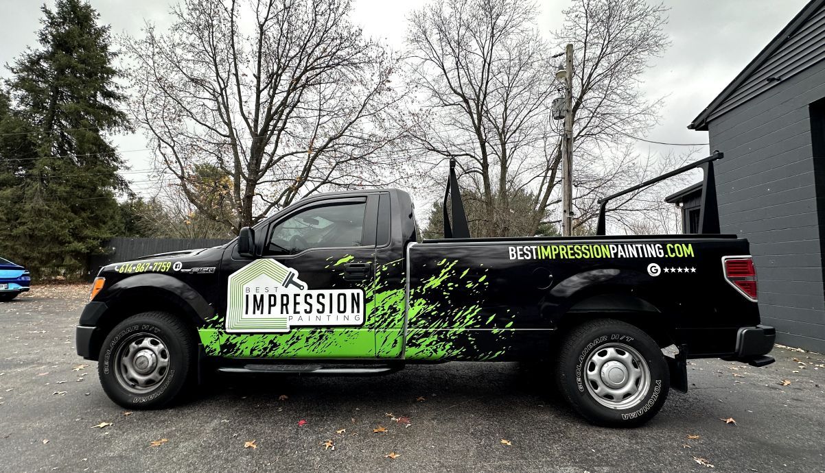 A black and green truck is parked in front of a building.