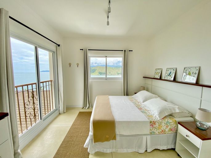 Um quarto com uma cama grande e uma varanda com vista para o oceano