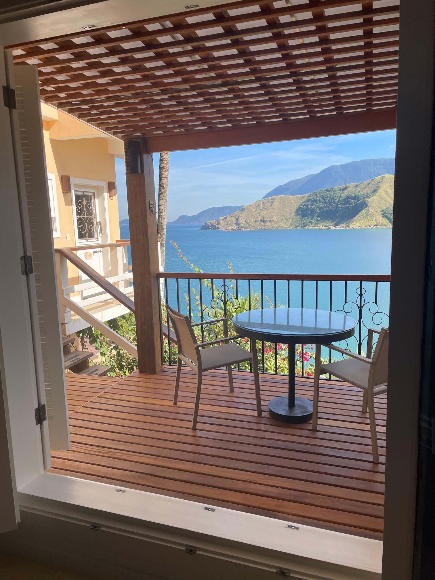 Uma vista do oceano de uma varanda com mesa e cadeiras.