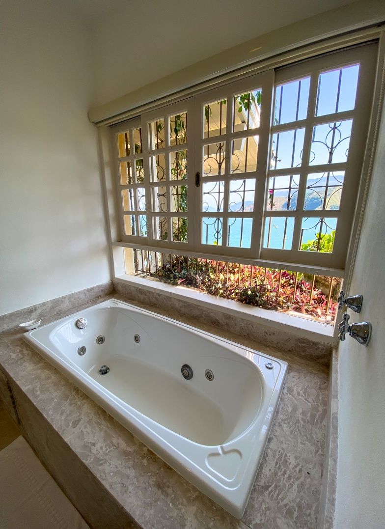 Um banheiro com banheira de hidromassagem e janela.