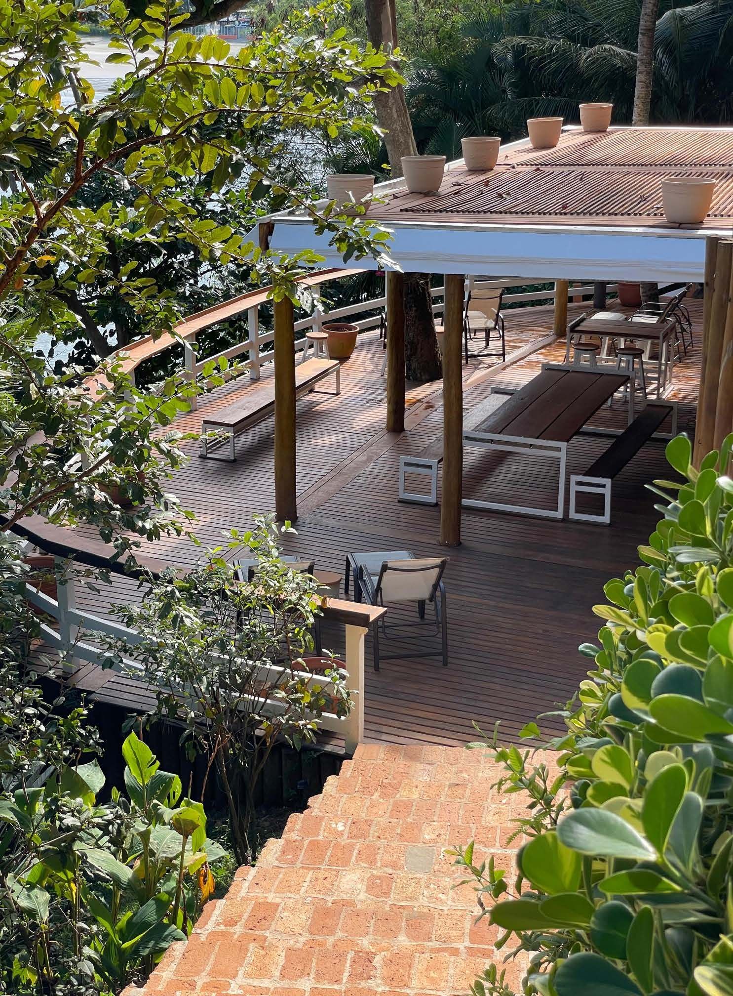 Um deck de madeira com uma mesa e cadeiras cercado por árvores.