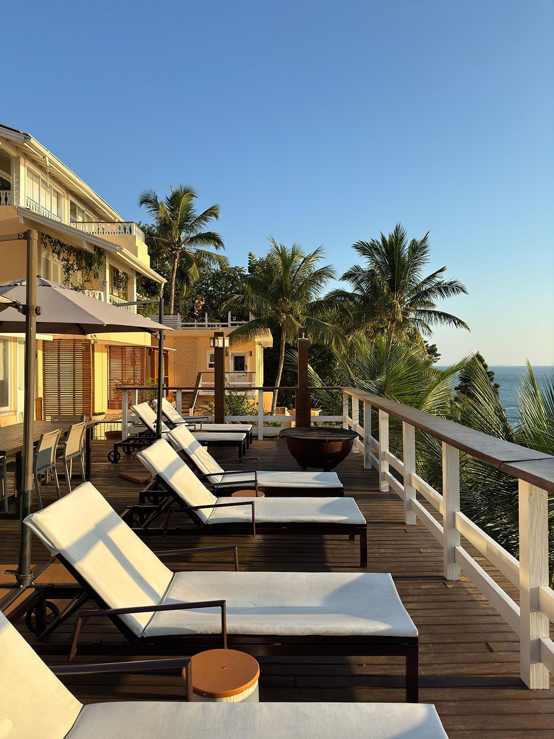 Uma fileira de espreguiçadeiras em um deck com vista para o oceano.
