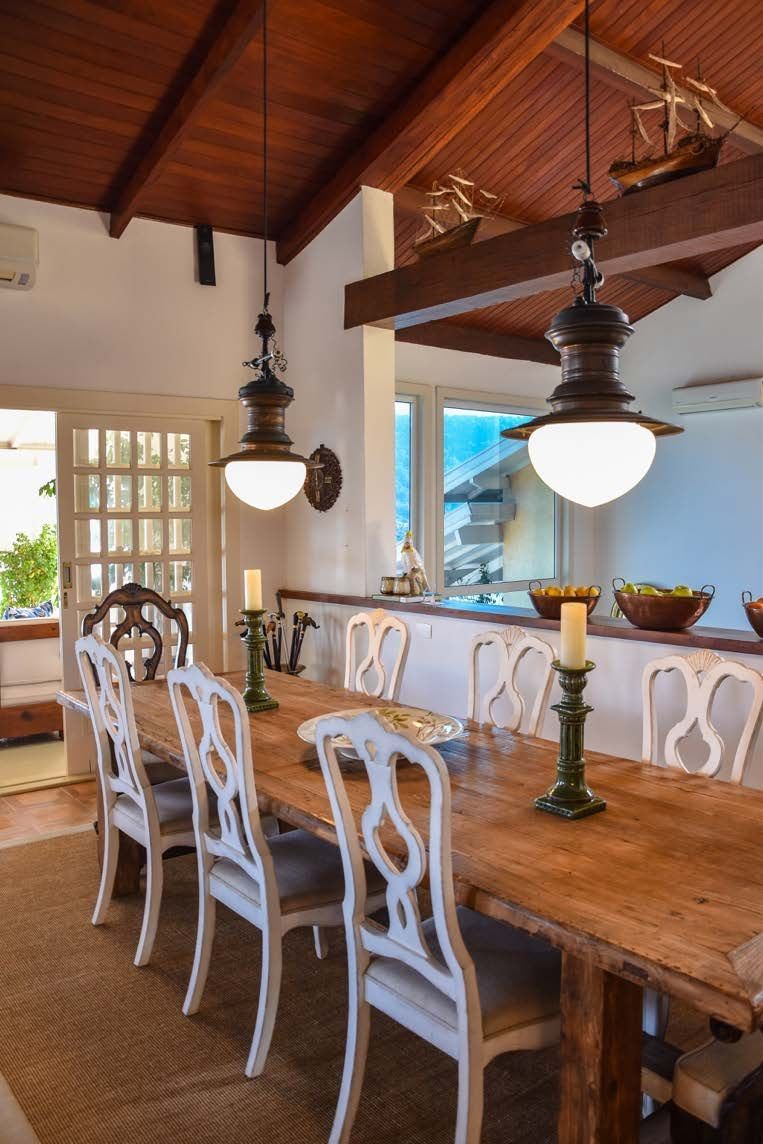 Uma sala de jantar com uma longa mesa de madeira e cadeiras brancas