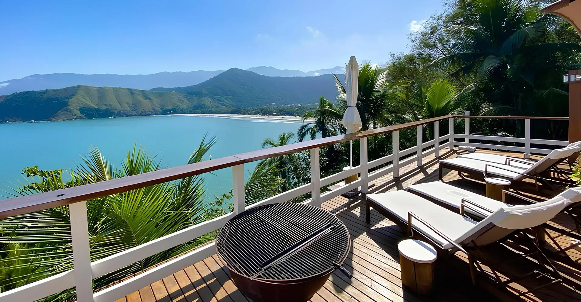Uma varanda com vista para um corpo de água com montanhas ao fundo