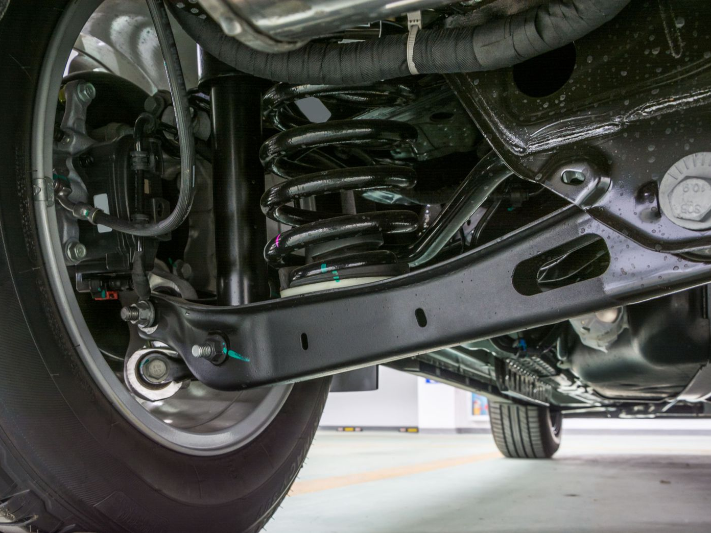 Undercarriage of a vehicle showing black suspension components, wheel, and tire.