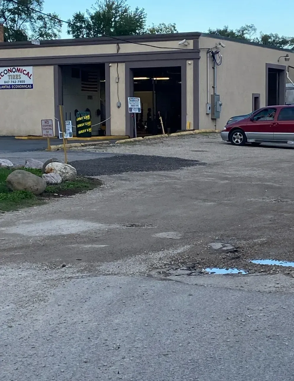 A car wash with open bays and a red SUV parked outside on a gravel lot.
