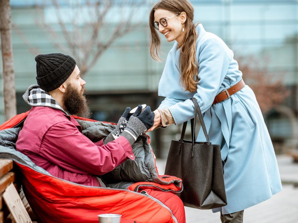 woman giving something to a homeless man in a wheelchair