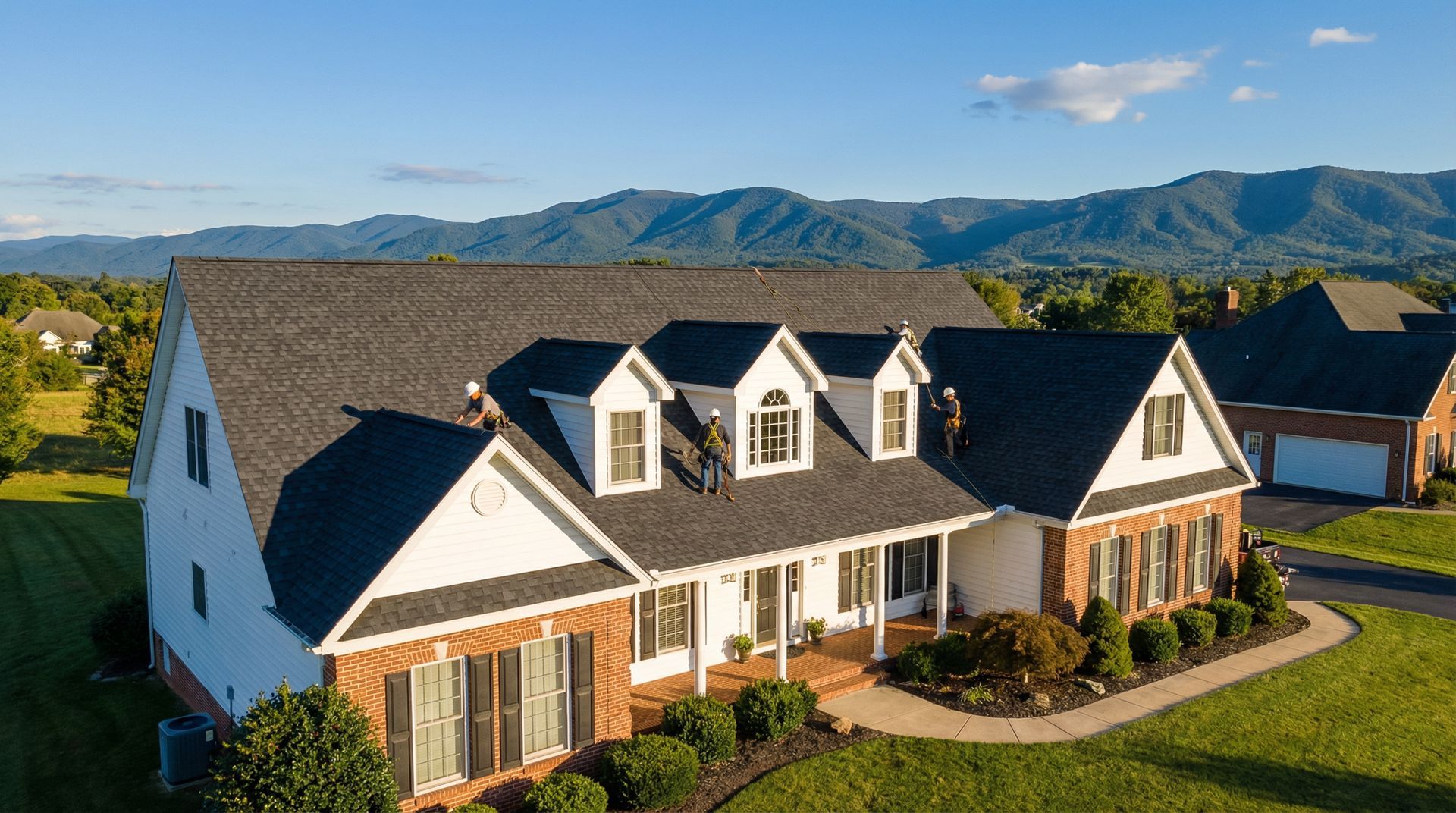 Large suburban house with white siding, dark roof, and brick accents in a landscaped neighborhood with mountains behind