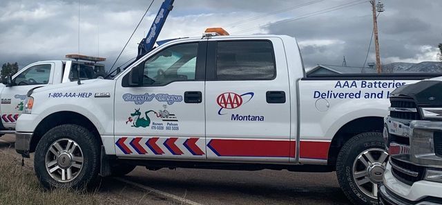Two tow trucks are parked next to each other in a field.