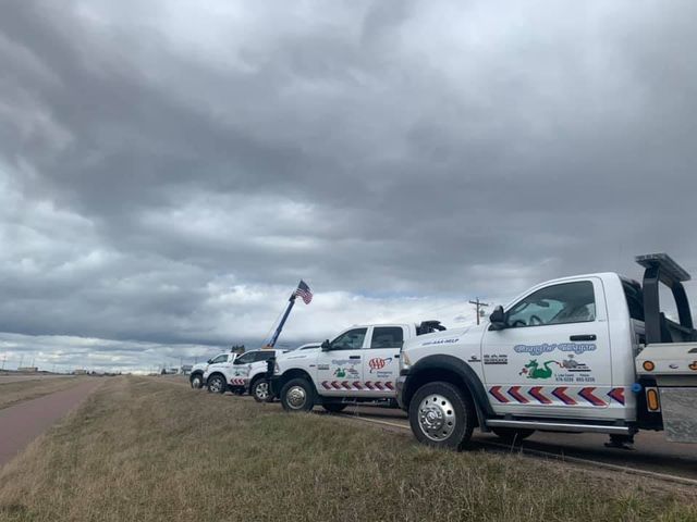 A row of tow trucks are parked on the side of the road.
