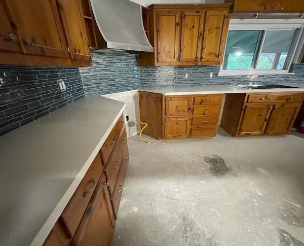 A kitchen with wooden cabinets , a sink , and a window.