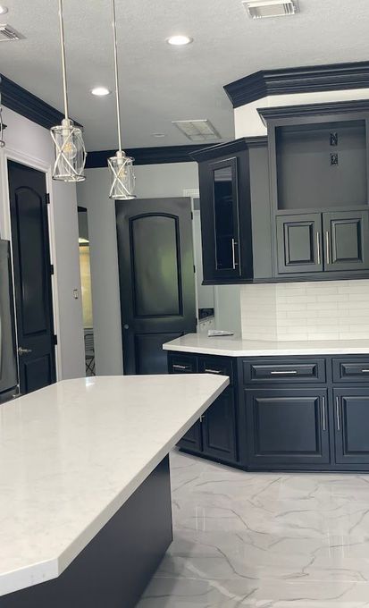 A kitchen with black cabinets and white counter tops