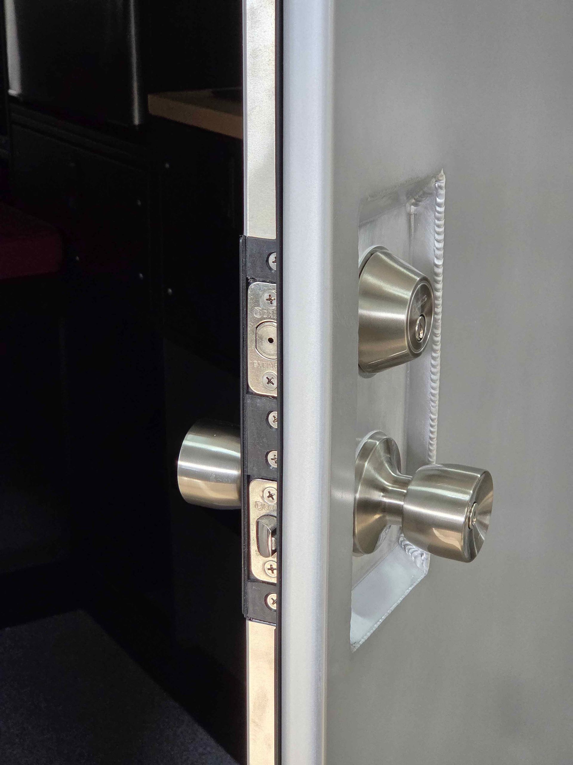 Metal door with a doorknob and deadbolt, and the strike plate.