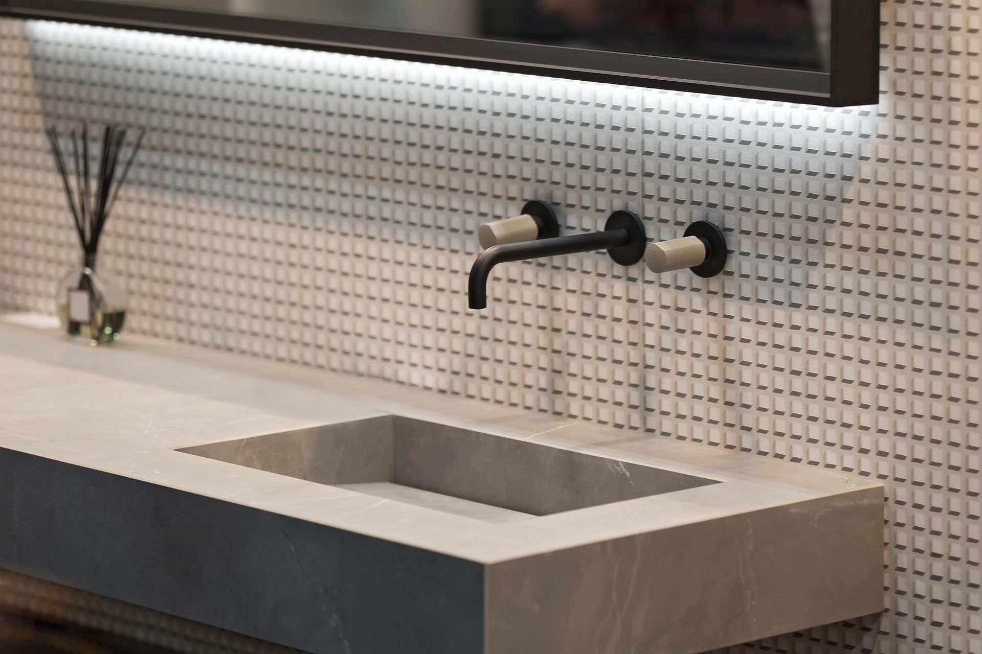 Modern bathroom with concrete sink, black faucet, and white tiled backsplash.