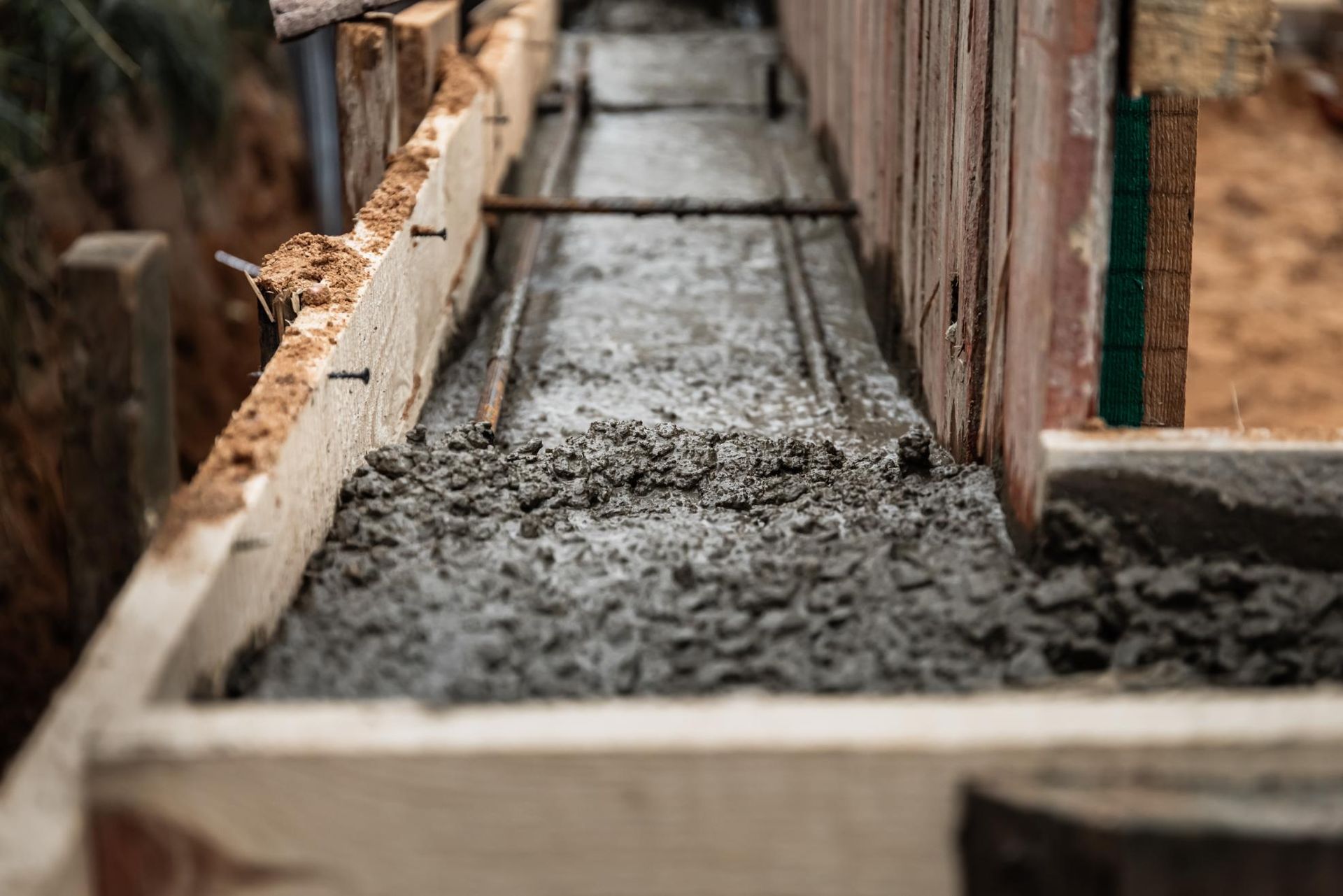 Fresh concrete poured into wooden forms, with rebar reinforcement.