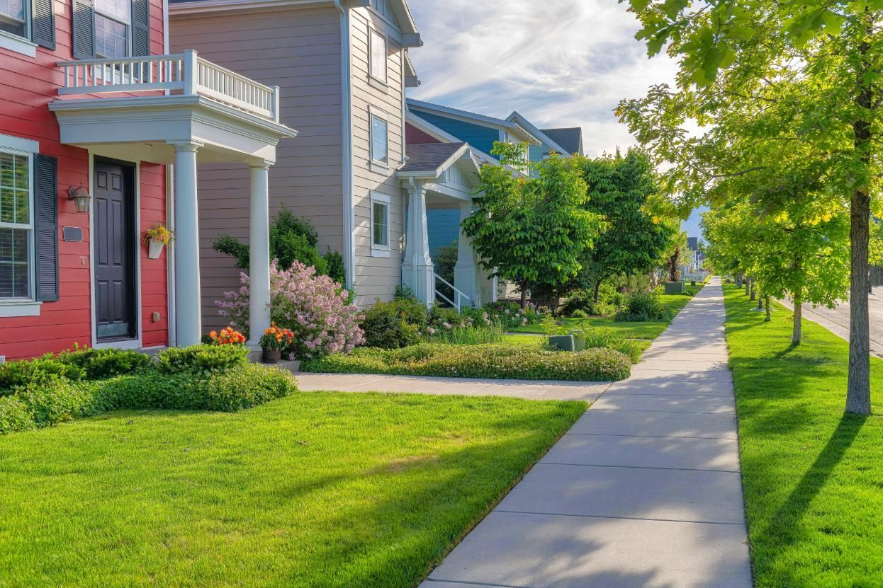 Row of colorful houses with green lawns and sidewalks on a sunny day.
