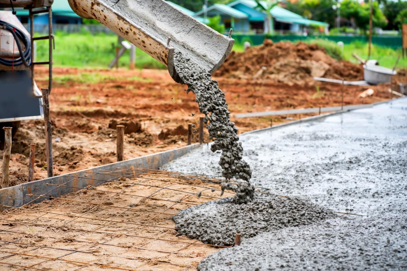 Concrete being poured from a truck, creating a sidewalk in a construction setting.
